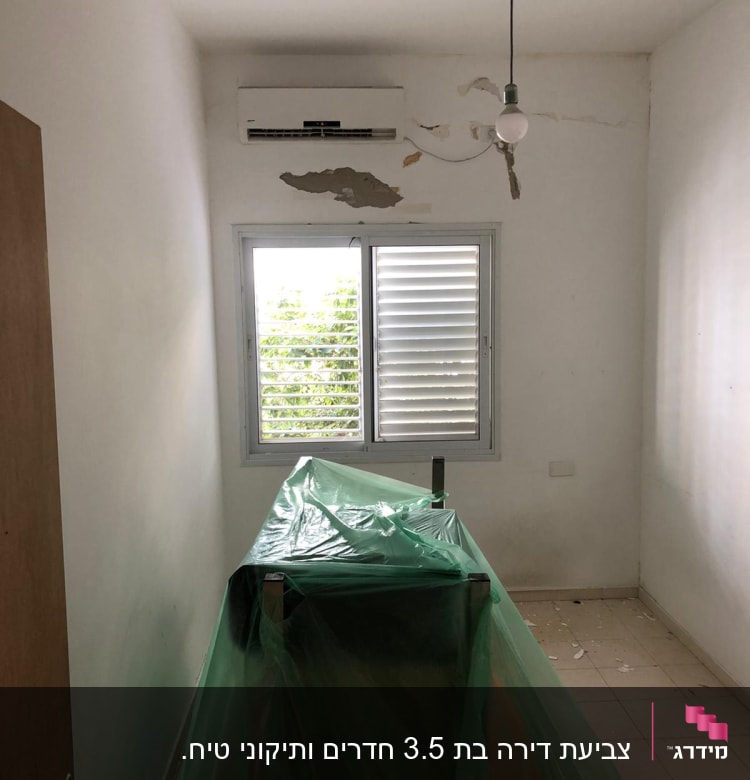 חדר עם קירות מתקלפים, כיסוי פלסטיק ירוק על רהיט